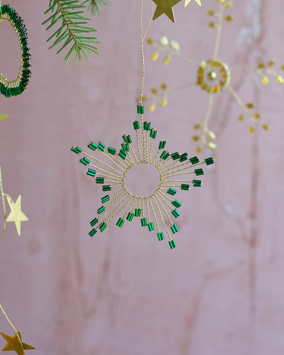 Decorative hanging stars and green circular ornaments on a pink background