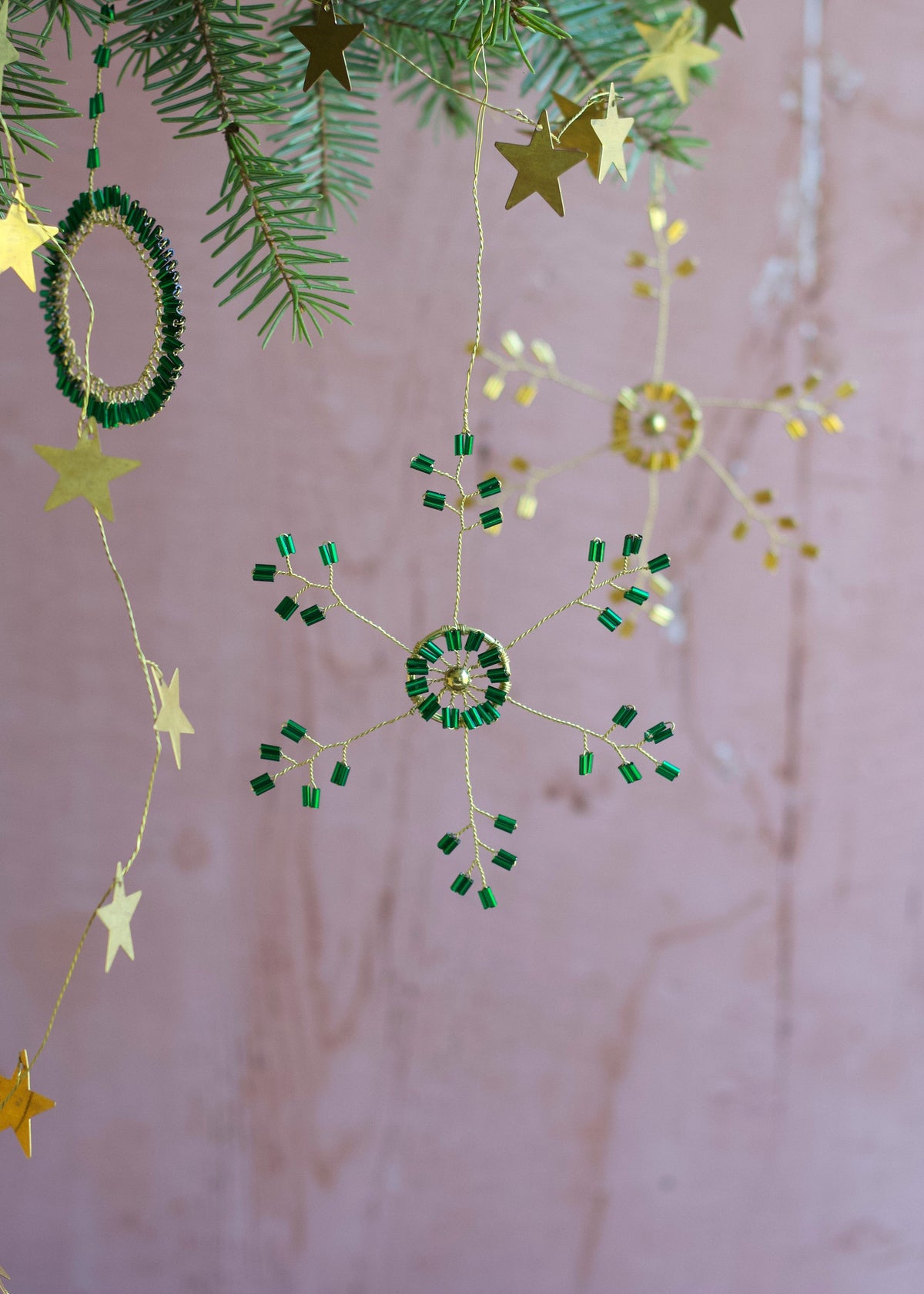 Decorative string with stars and green circular ornaments on a pink background