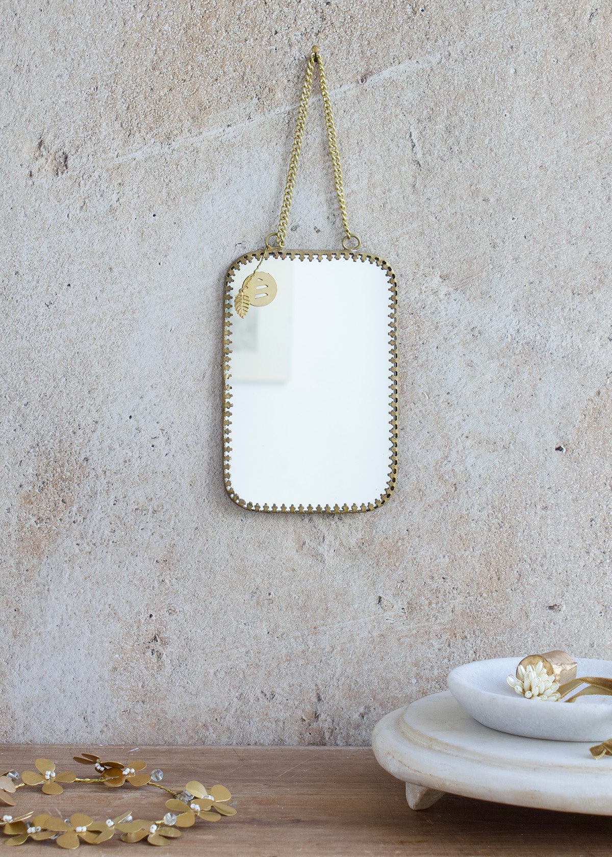 Medium rectangular mirror with rounded corners, brass frame and double chain hanger, styled on a stone wall with golden accessories and a marble tray.
