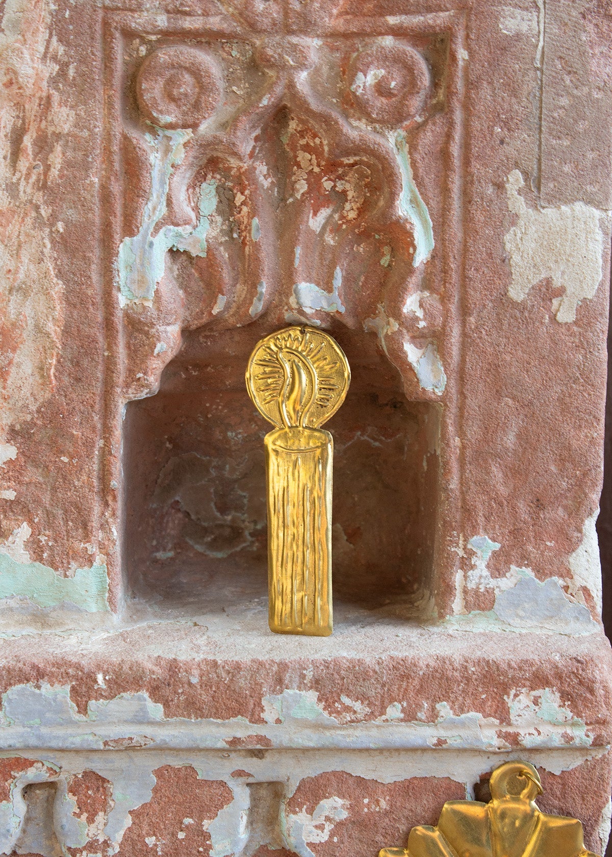 Decorative stone panel with gold emblem and peeling paint