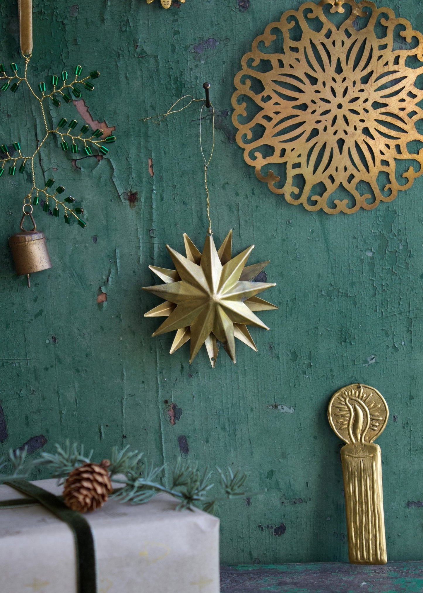 Decorative gold star ornament on a textured green wall with other ornaments.