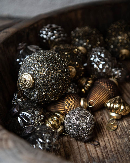 Decorative Christmas ornaments in black, gold, and bronze on a wooden surface