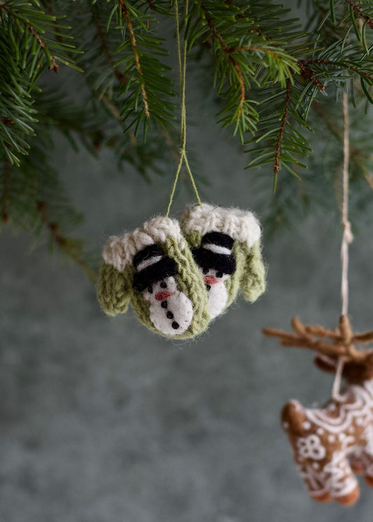 Knitted snowman ornament hanging on a tree branch with a blurred background