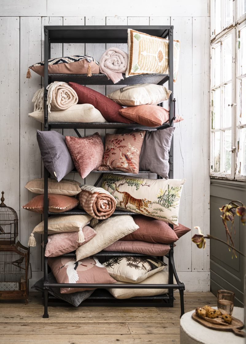 Black metal shelf with pillows and blankets against a white wall.