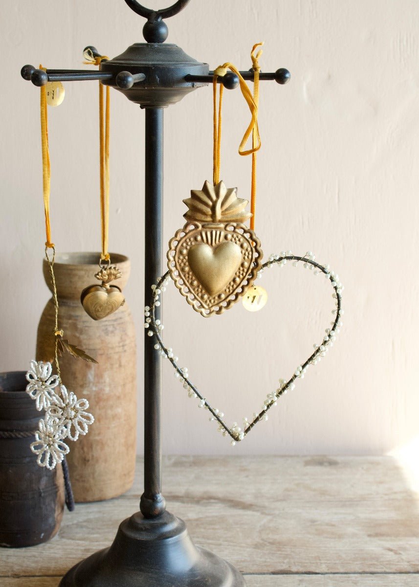 Collection of brass and beaded heart and flower ornaments hanging from a black metal stand
