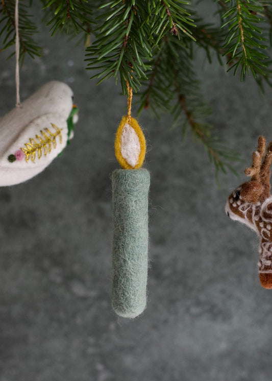 Green cylindrical ornament hanging from a tree branch with other ornaments.