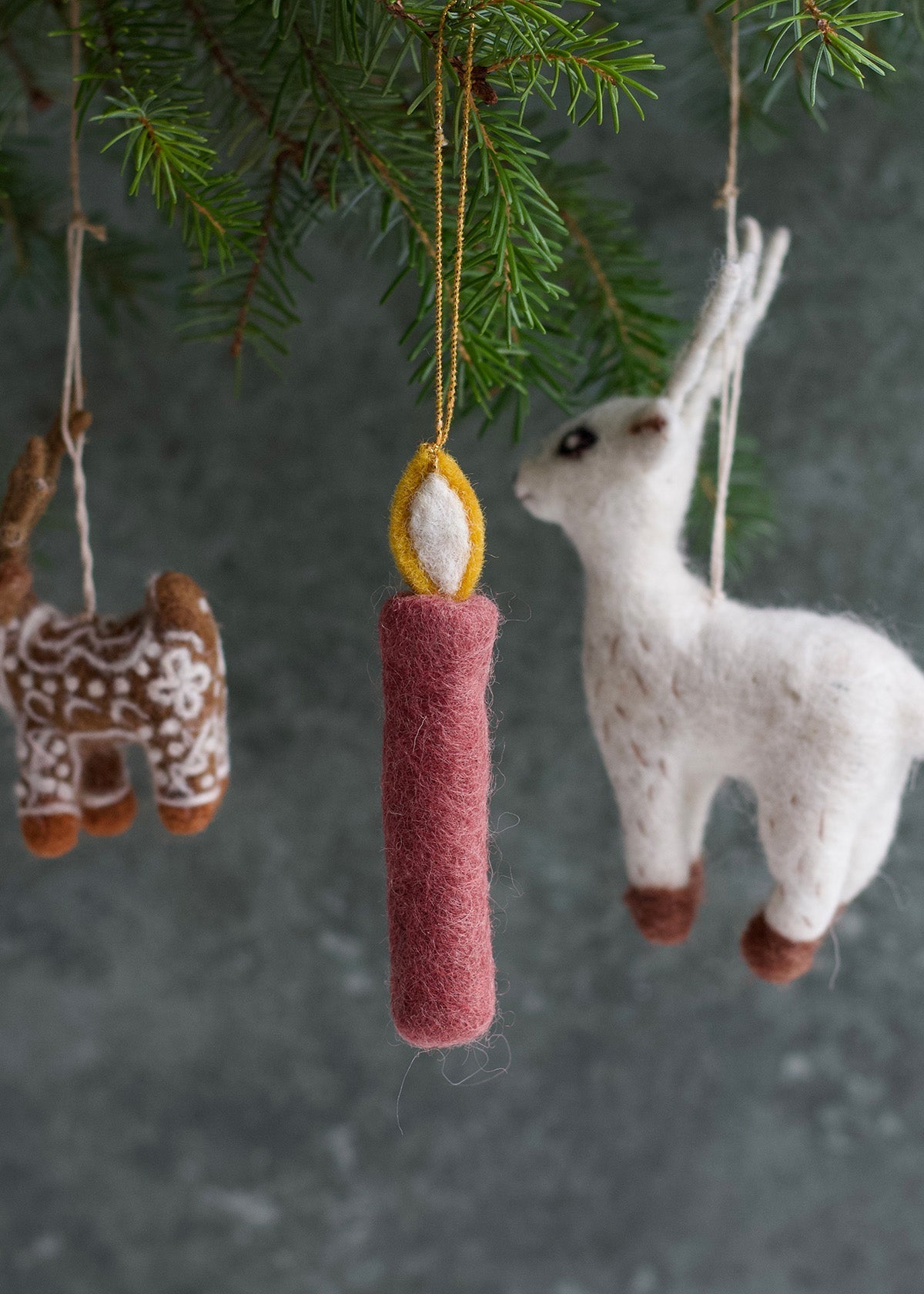 Decorative ornaments including a llama, candle, and deer hanging from a branch.