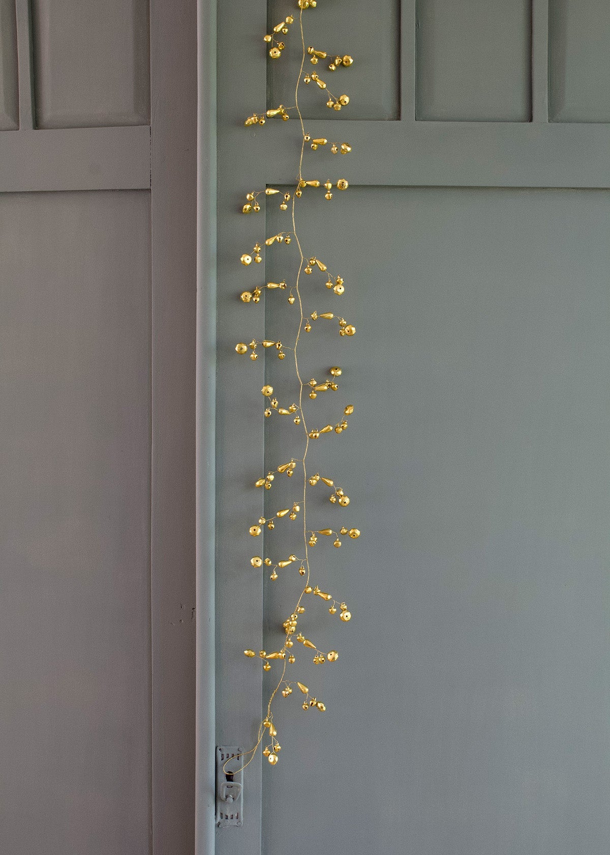 String of gold lights hanging vertically on a gray wall.