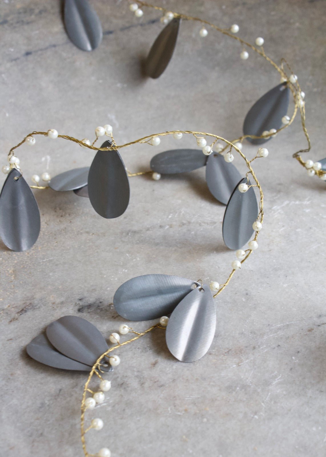 Necklace with gray teardrop-shaped pendants and pearl accents on a neutral background
