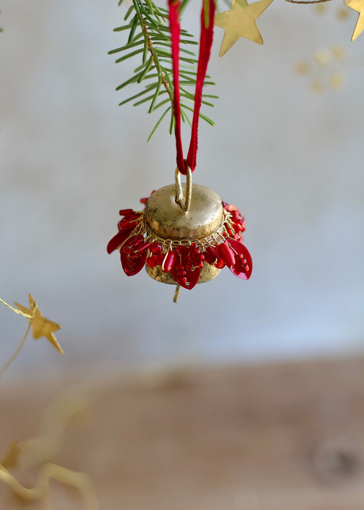 Decorative Christmas ornament with red berries and gold accents on a tree branch.
