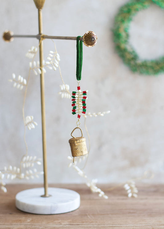 Decorative bell ornament with beads on a stand against a neutral background