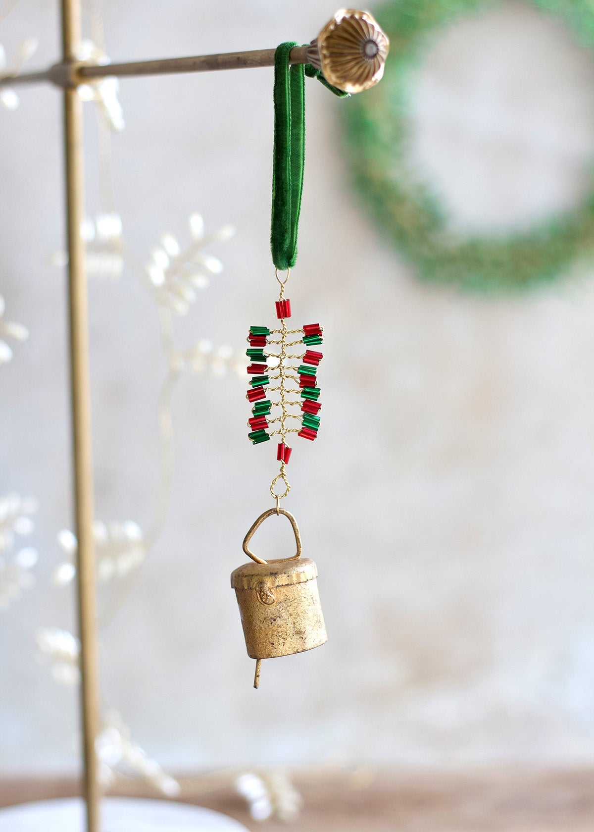 Decorative hanging ornament with gold bell and red beads on a blurred background