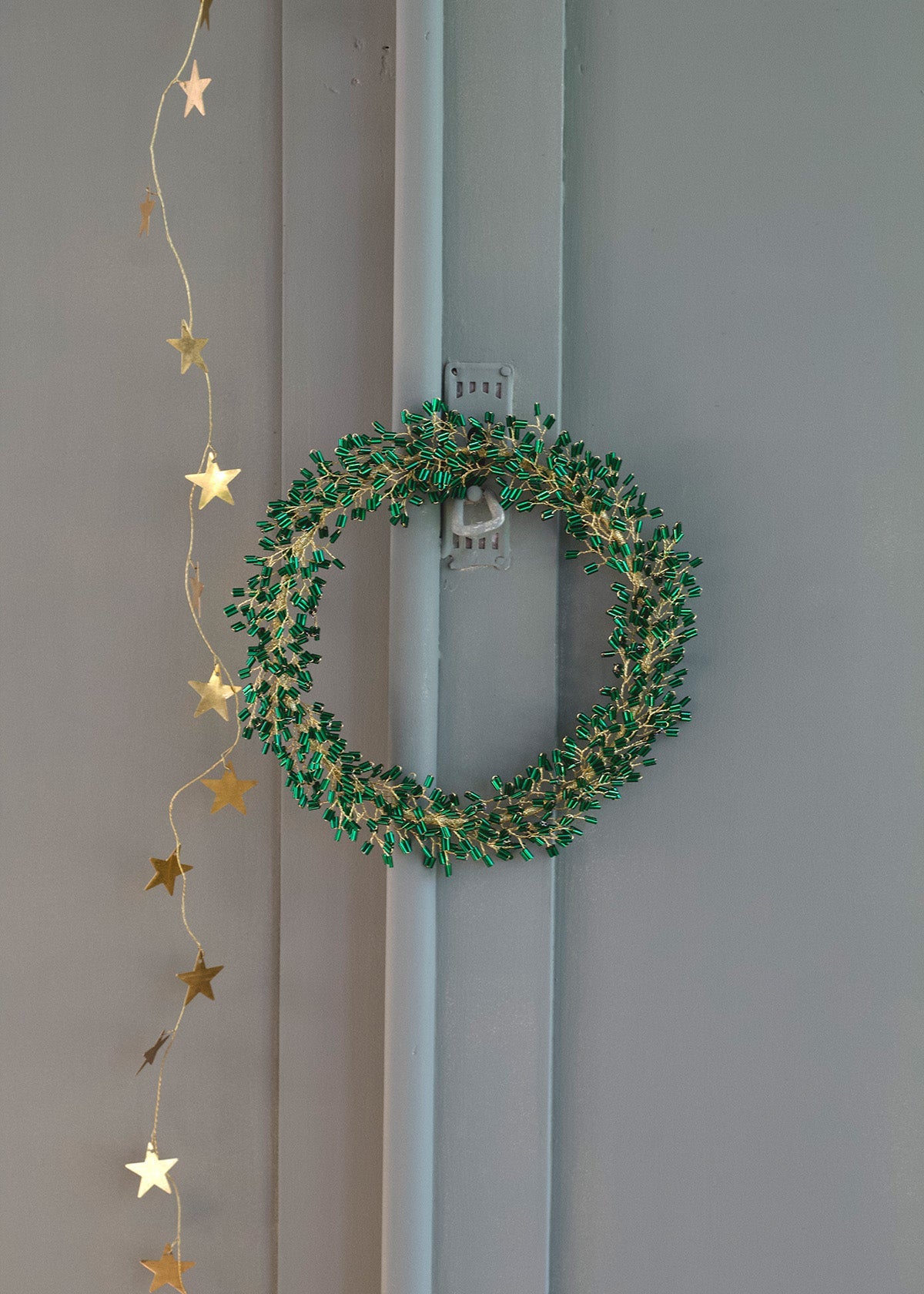 Green wreath with gold stars hanging on a gray door