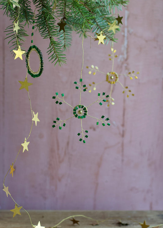 Decorative string with stars and green beads hanging against a pink wall.