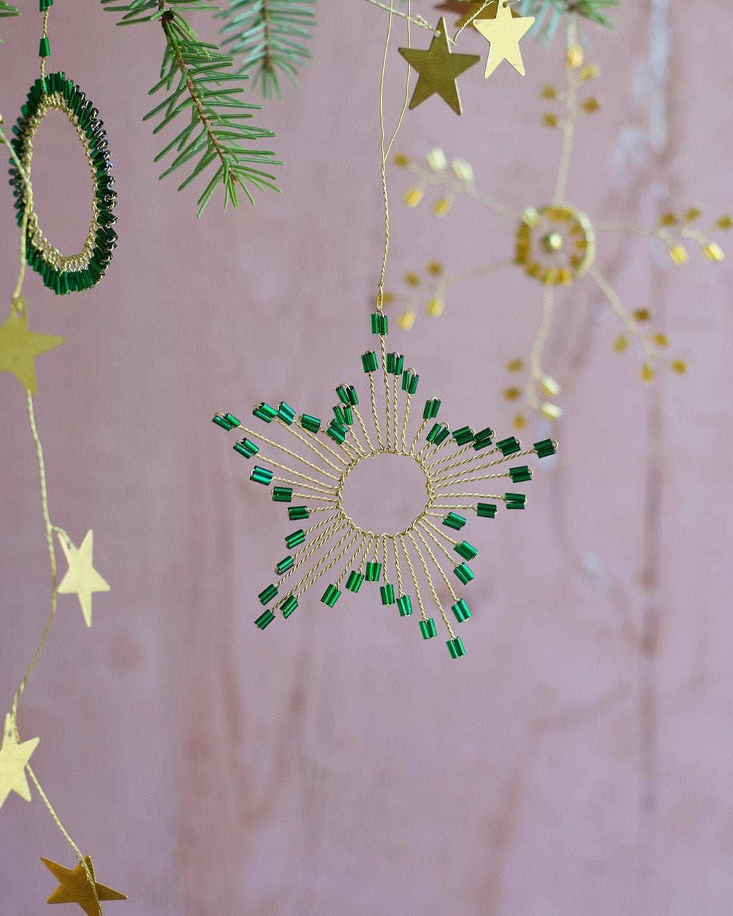 Decorative hanging stars and green circular ornaments on a pink background
