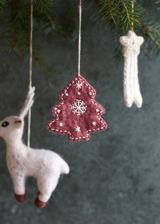 Felt Christmas tree ornament with snowflake design hanging from a branch.