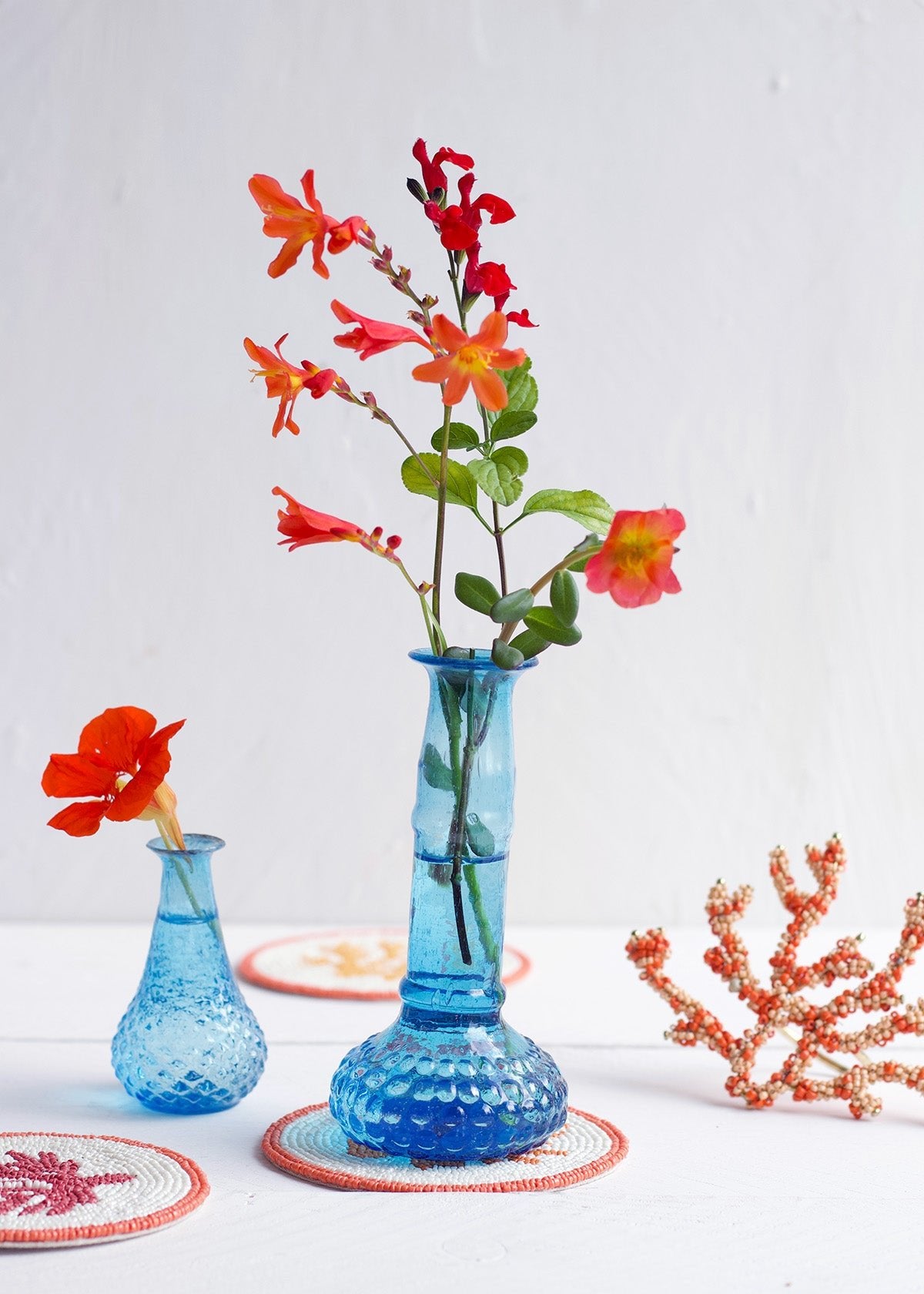 Blue textured vase with red flowers on a white surface