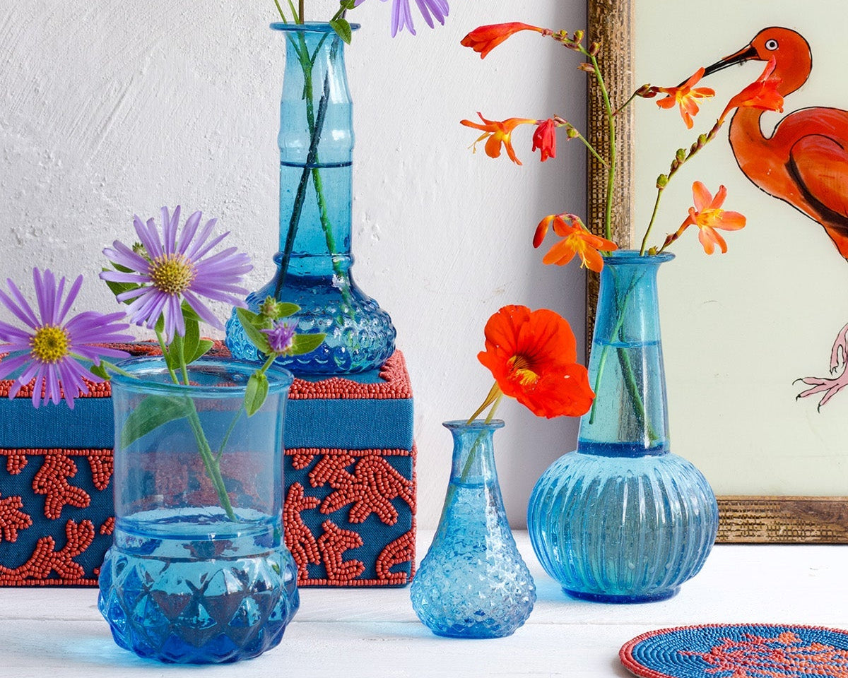 Decorative blue vases with flowers on a white surface, framed artwork in the background.