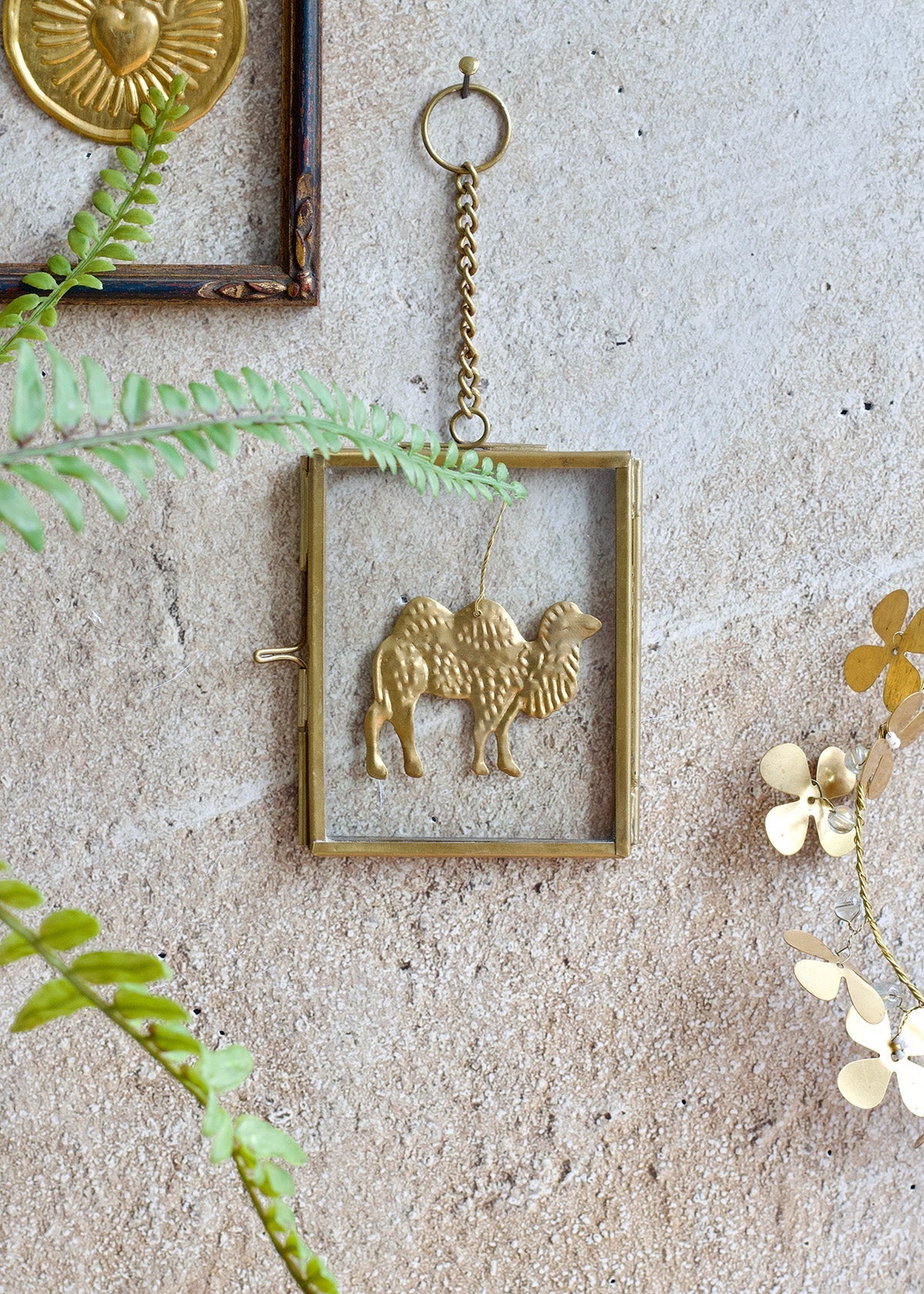 Decorative wall hanging with a gold frame and animal design on a textured wall.