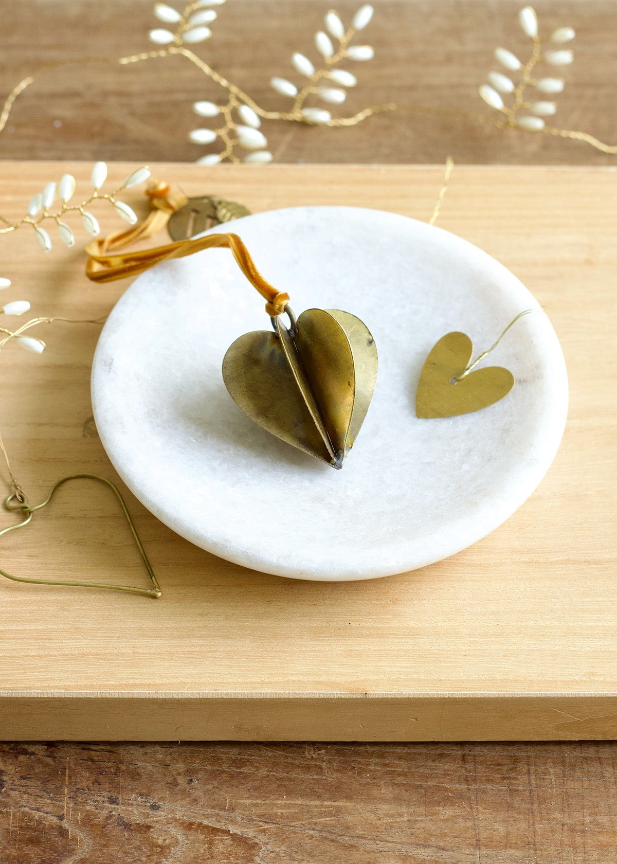 Decorative heart-shaped objects on a marble coaster with a wooden background