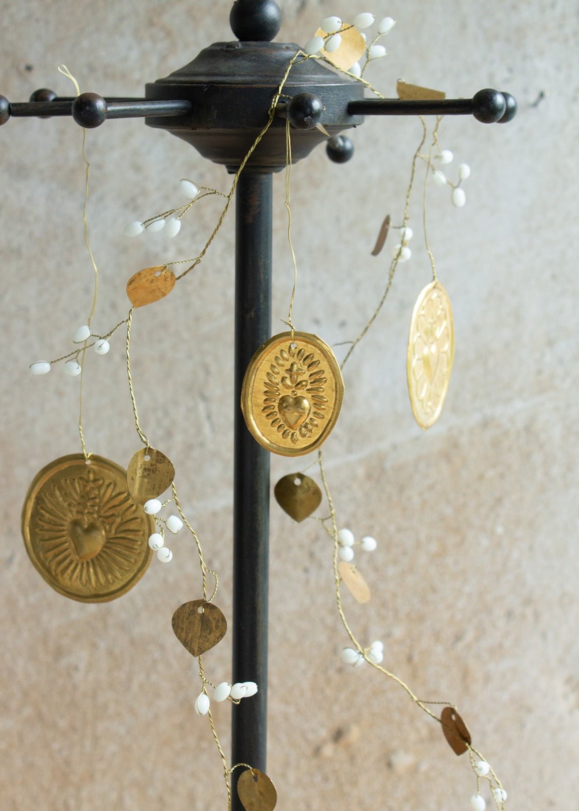 Handmade brass heart medallions hanging from a golden garland with white bead accents.