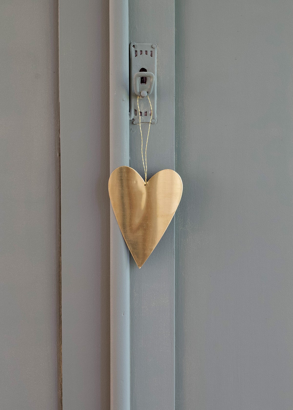 Wooden heart-shaped decoration hanging on a light blue wall.
