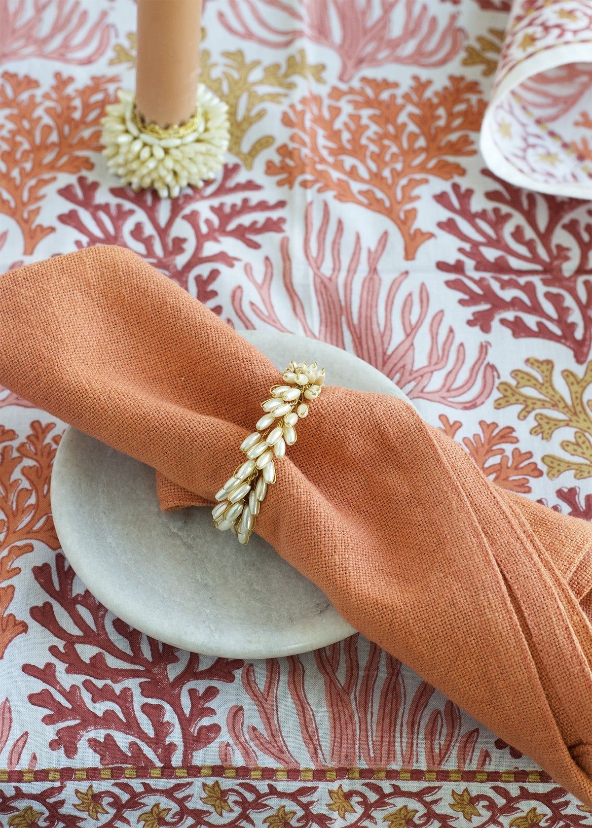 Napkin with a decorative ring on a coral-patterned tablecloth