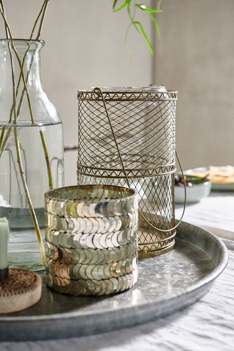 Decorative items including a wire mesh container and glass vase on a tray.