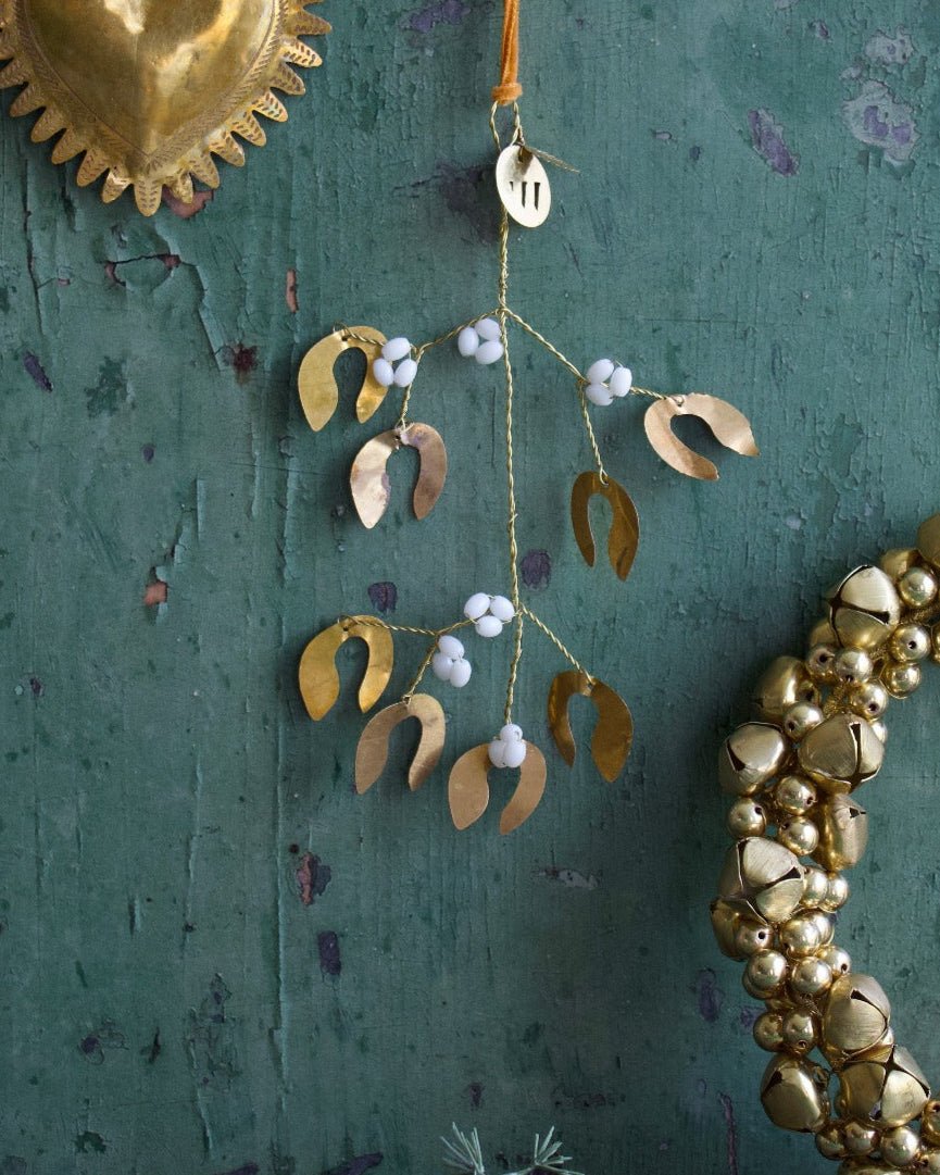 Decorative gold heart and leaf ornament on a textured green wall.