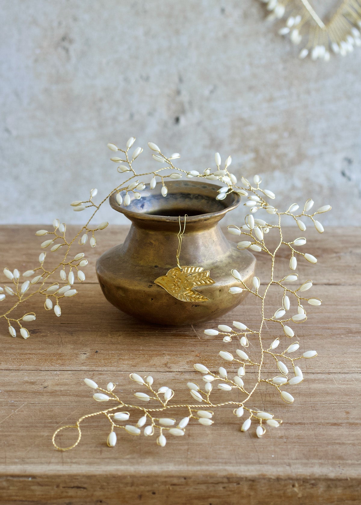 Bronze vase with decorative leaves on a wooden surface