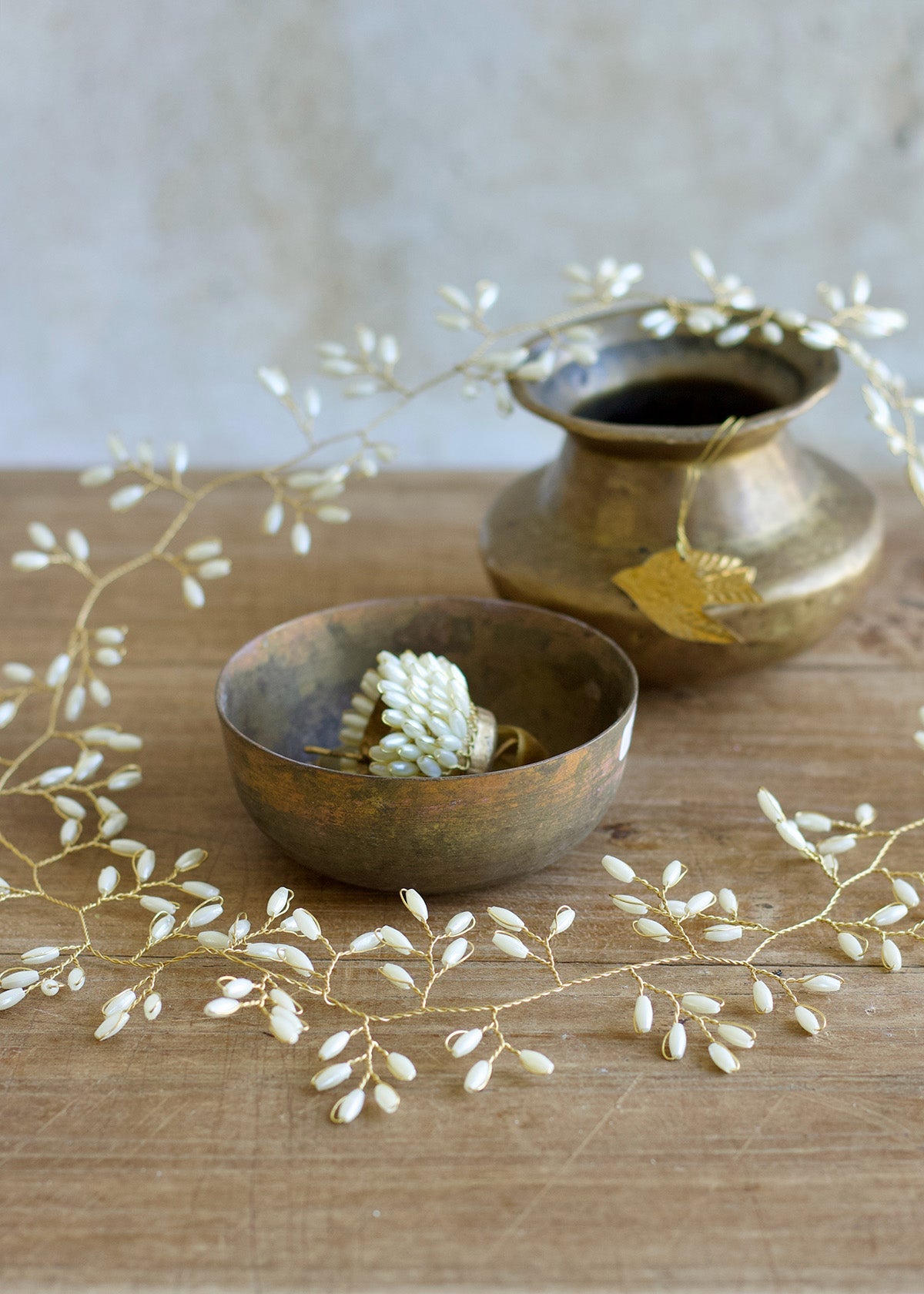 Two bronze bowls and a vase on a wooden surface with decorative white branches.