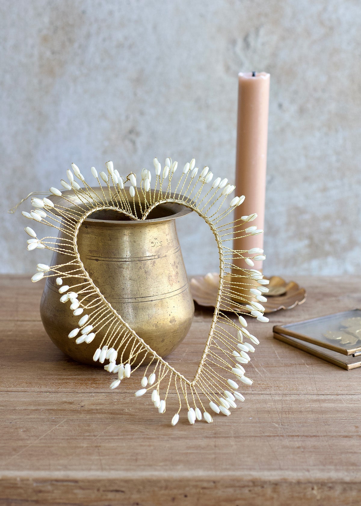 Decorative heart-shaped object with white beads on a wooden surface