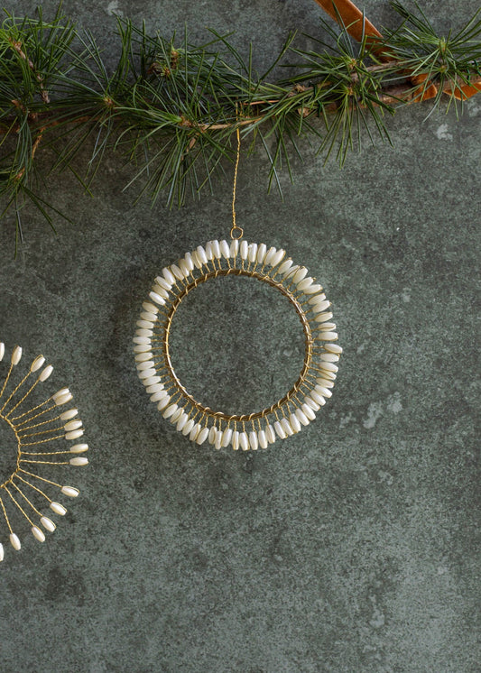 Decorative hoop ornament with white beads on a textured surface