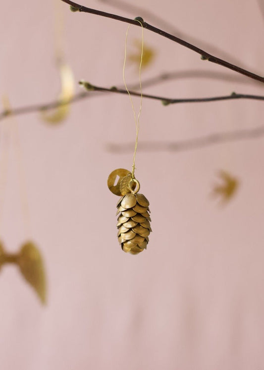 Small golden brass pinecone ornament with layered details, hanging from a branch.