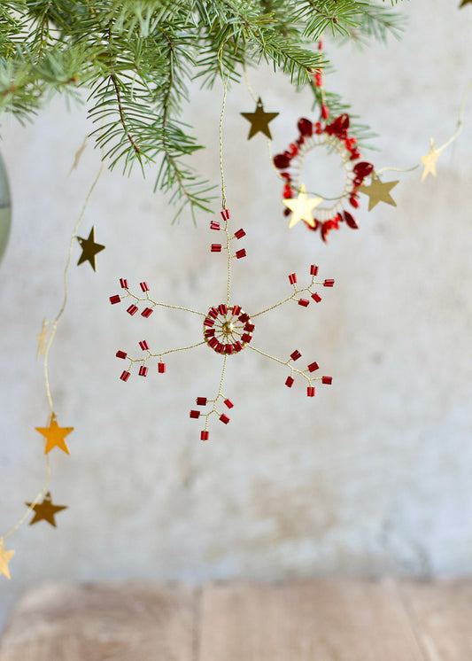 Decorative string with red and gold ornaments hanging from a Christmas tree.