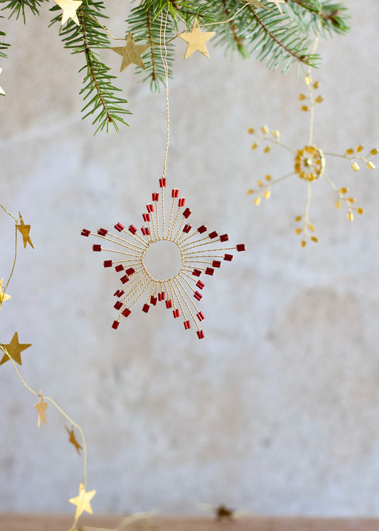 Decorative Christmas ornament with red and gold stars on a neutral background