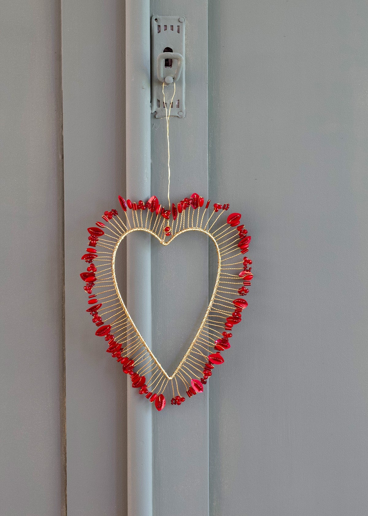 Heart-shaped decorative item with red elements on a light gray wall.