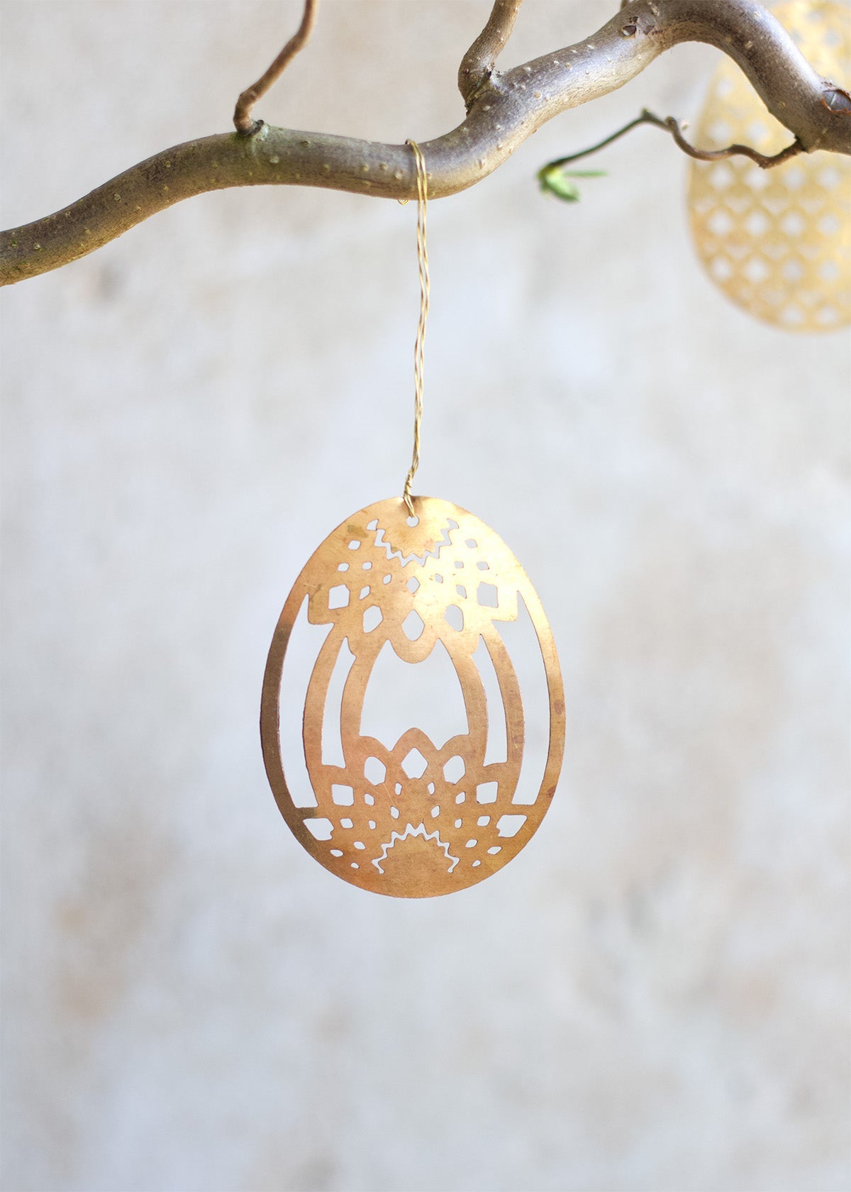 Gold decorative ornament hanging from a branch with a blurred background