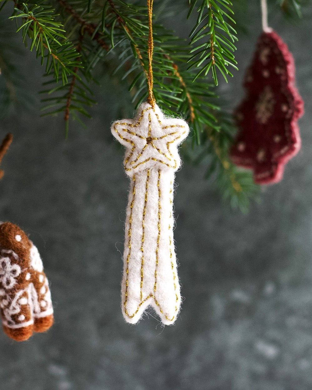 Decorative Christmas ornaments hanging on a tree branch with a dark background