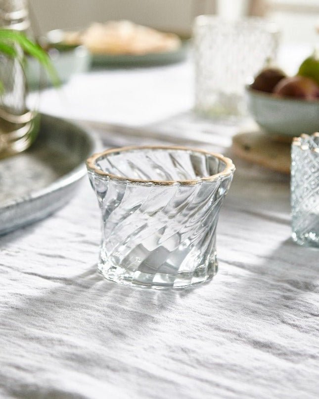 Clear glass votive holders on a marble table with a blurred background