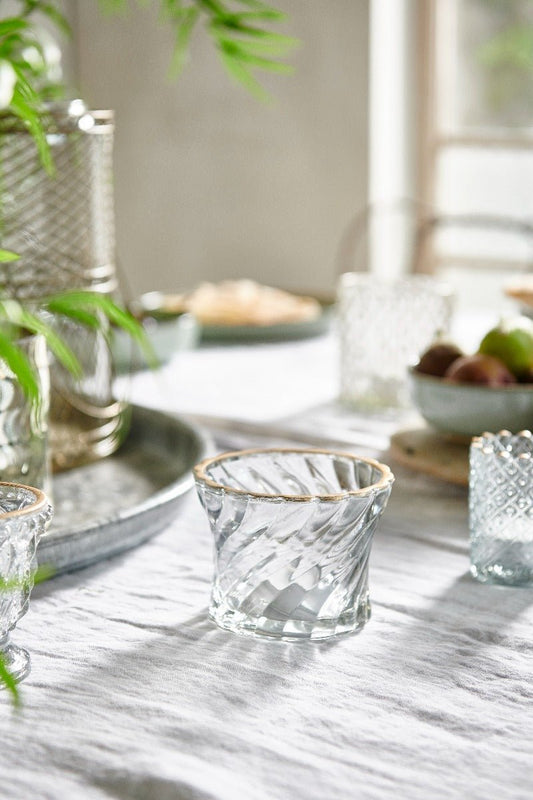 Clear glass candle holders on a marble table with a blurred background