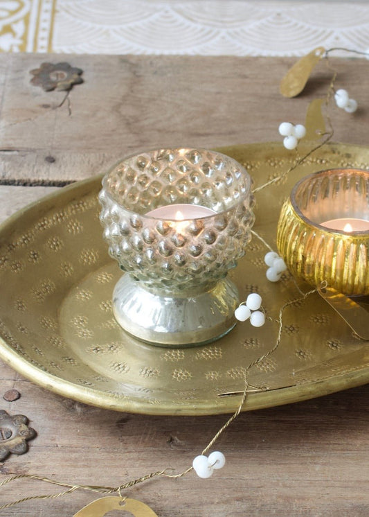 Decorative candle holders on a gold tray with a wooden background