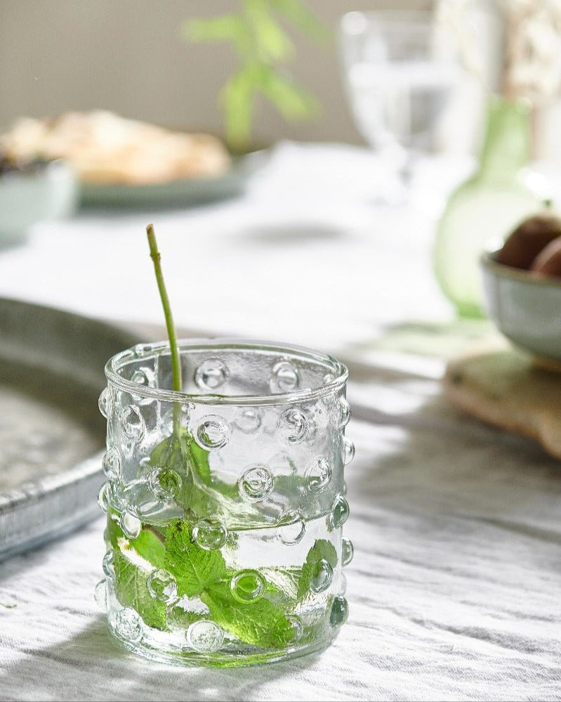 Clear glass with water and green leaves on a wooden table