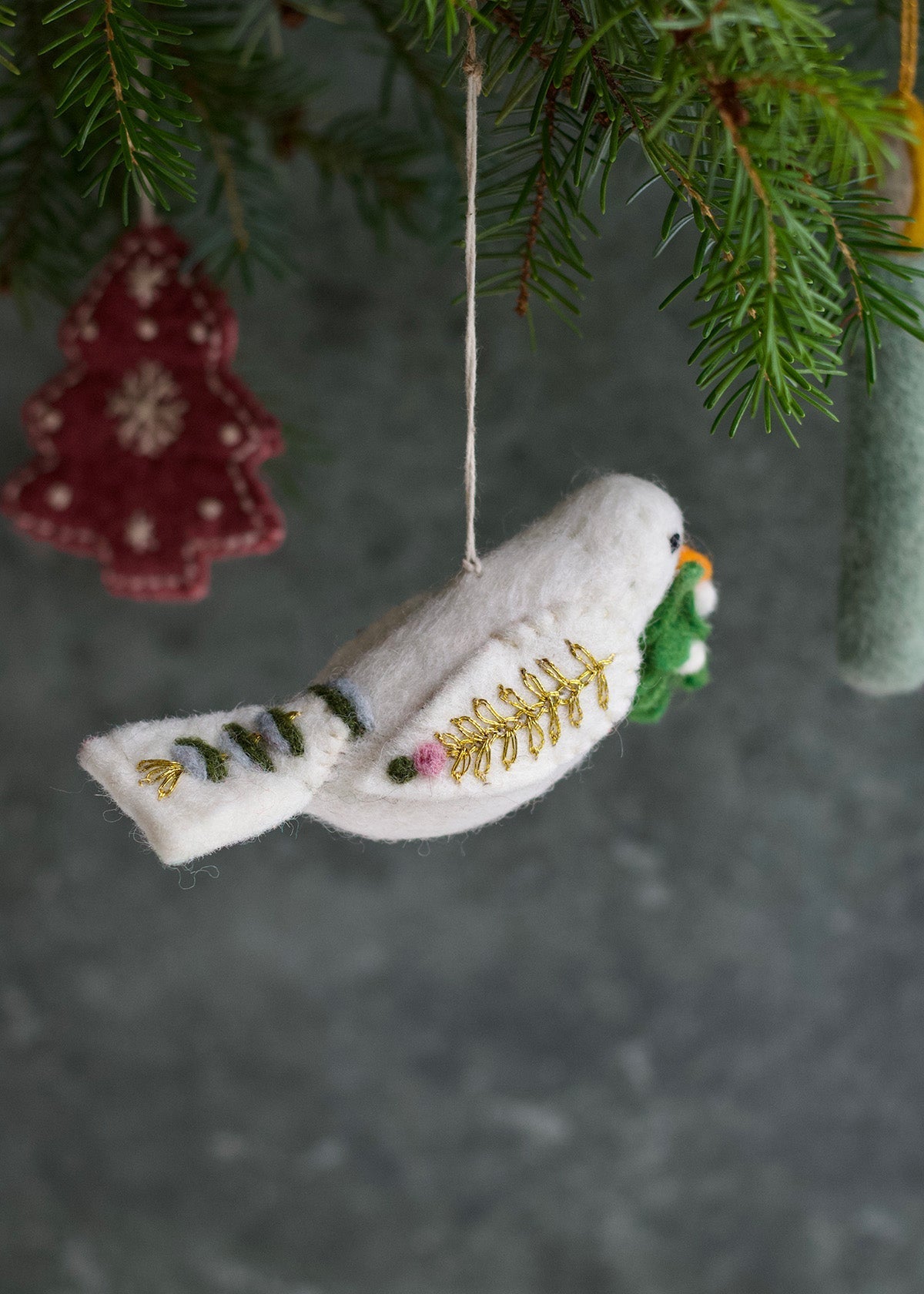 Decorative white dove ornament with greenery on a branch