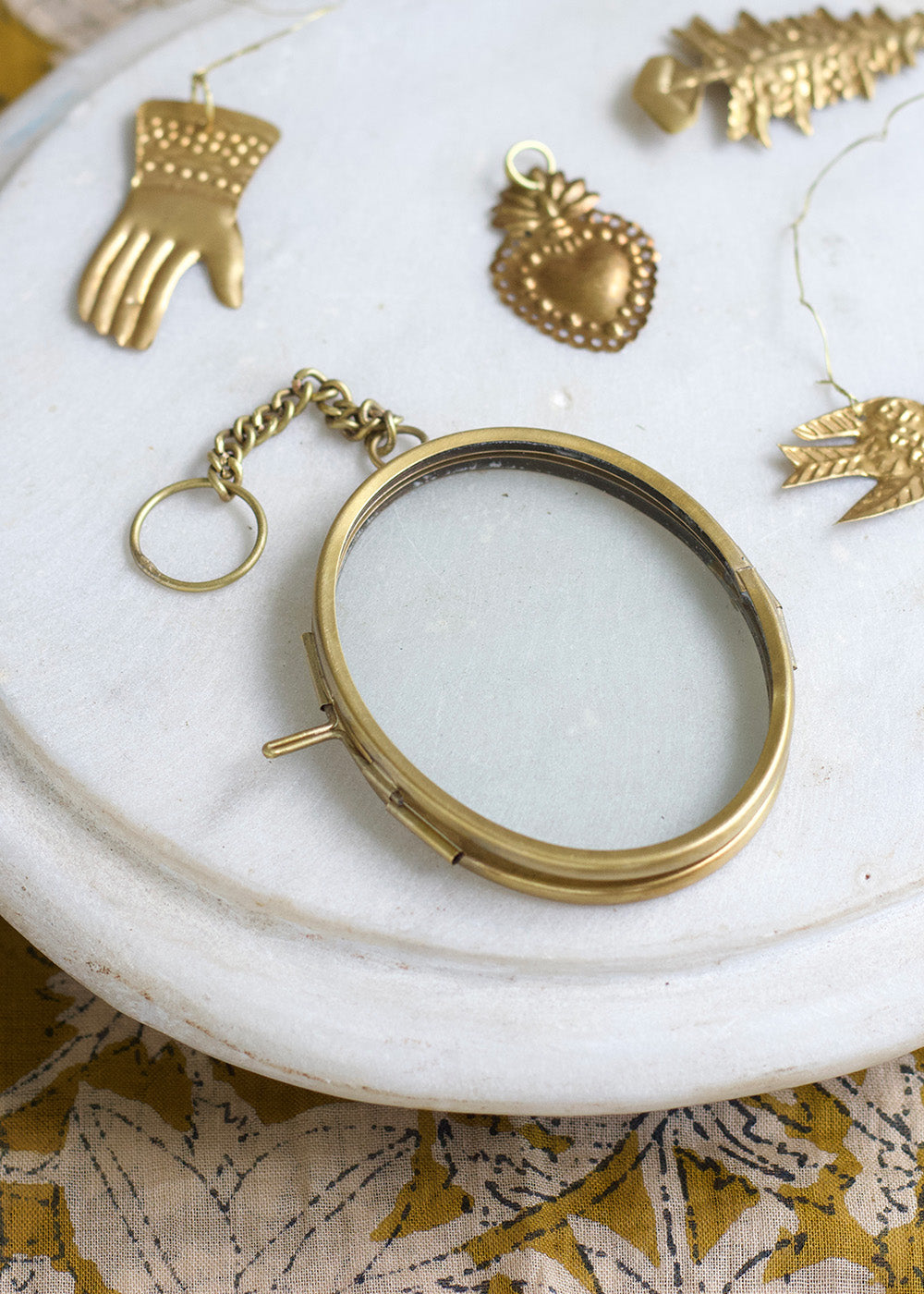 Gold locket on a marble surface with decorative items