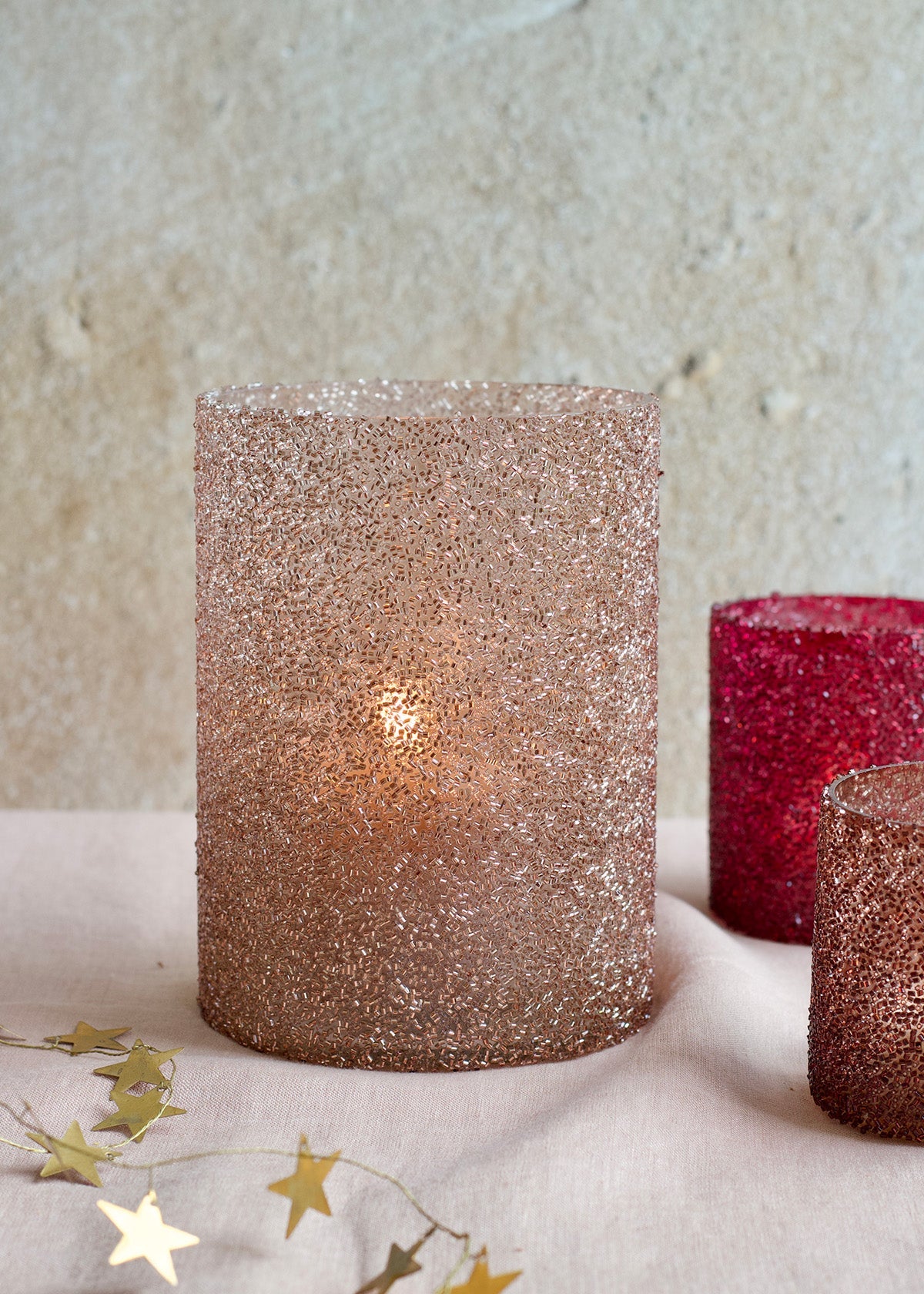 Glittery candles on a textured surface with star decorations.
