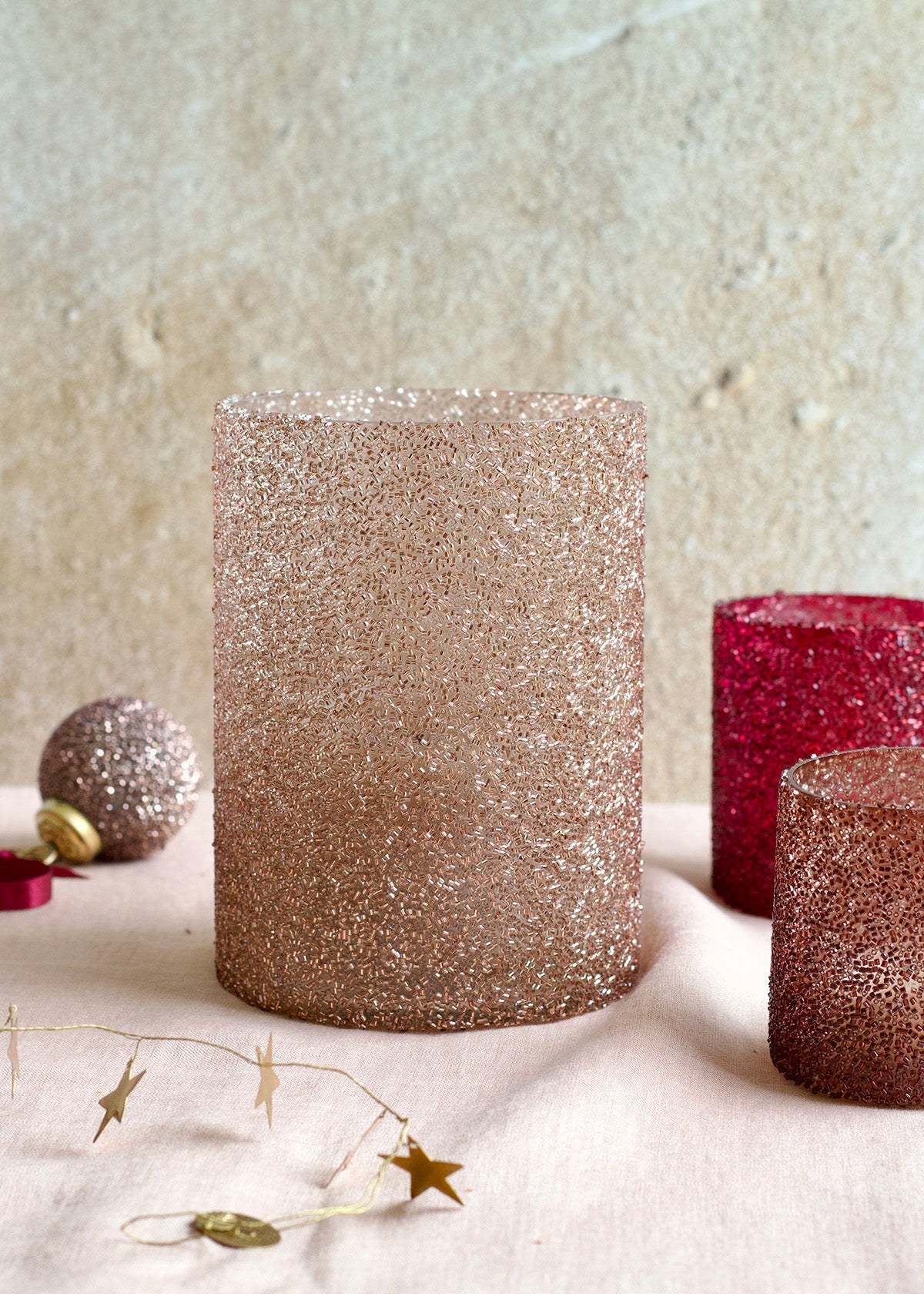 Glittery cylindrical candles on a textured surface with decorative elements.