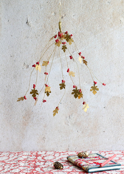 Decorative hanging plant with red berries on a textured wall background