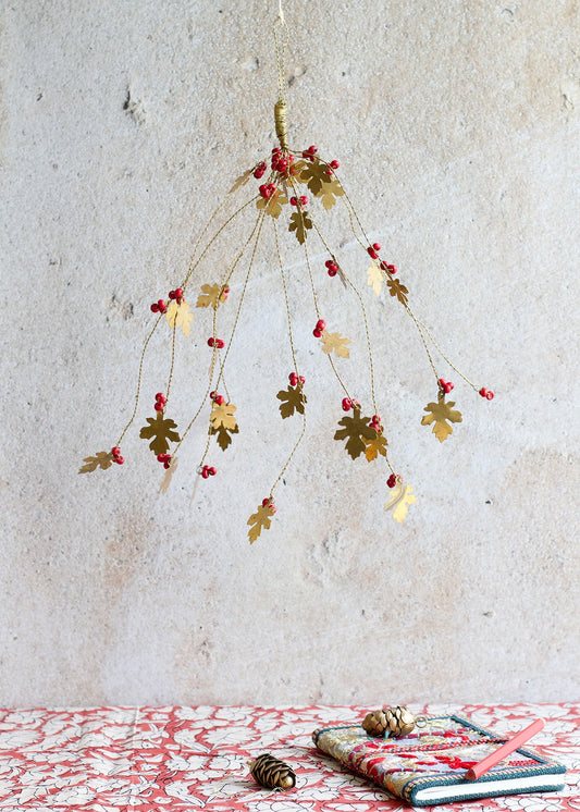 Decorative hanging plant with red berries on a textured wall background