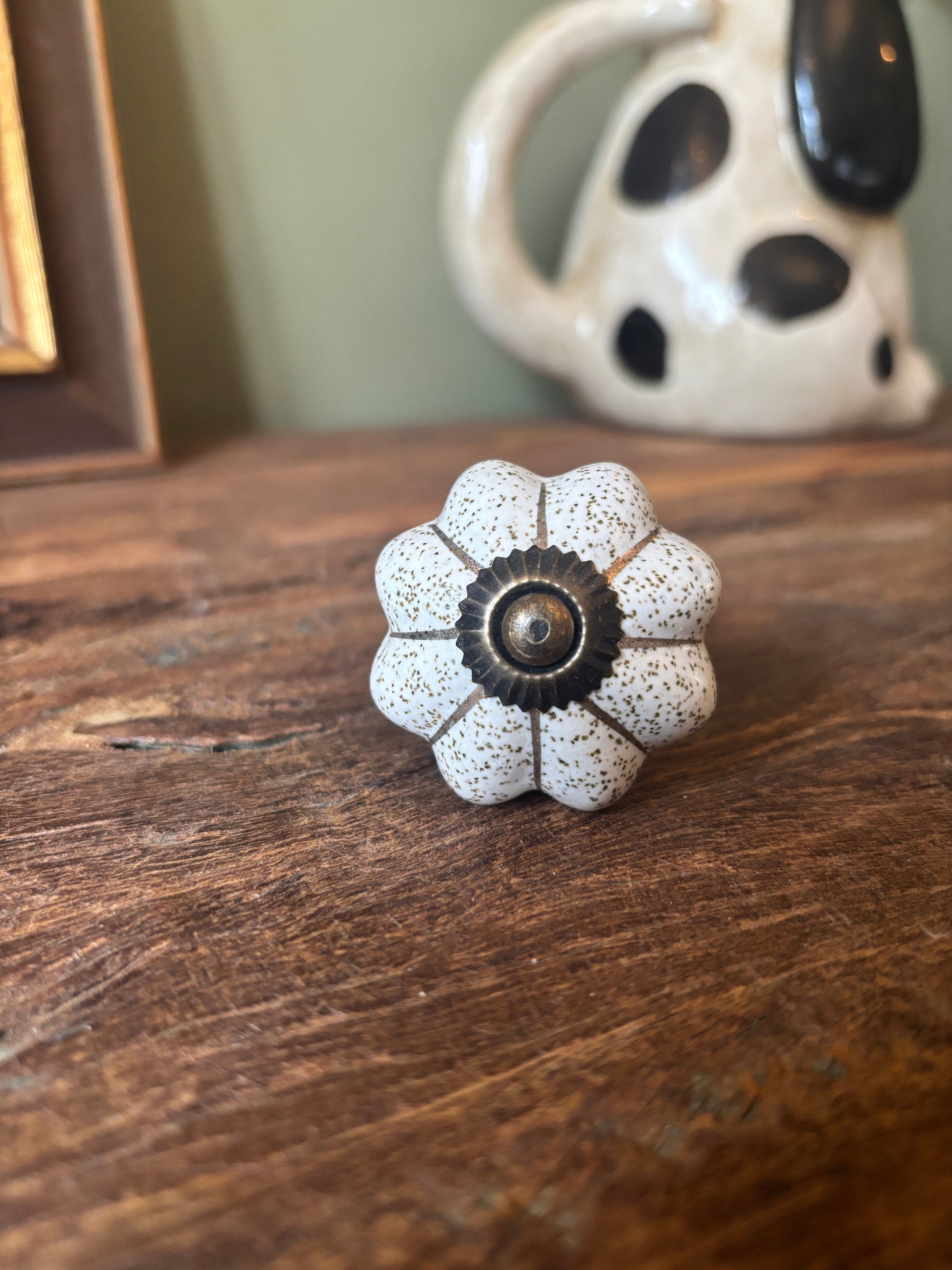 Decorative flower-shaped knob on a wooden surface with a ceramic pot in the background.